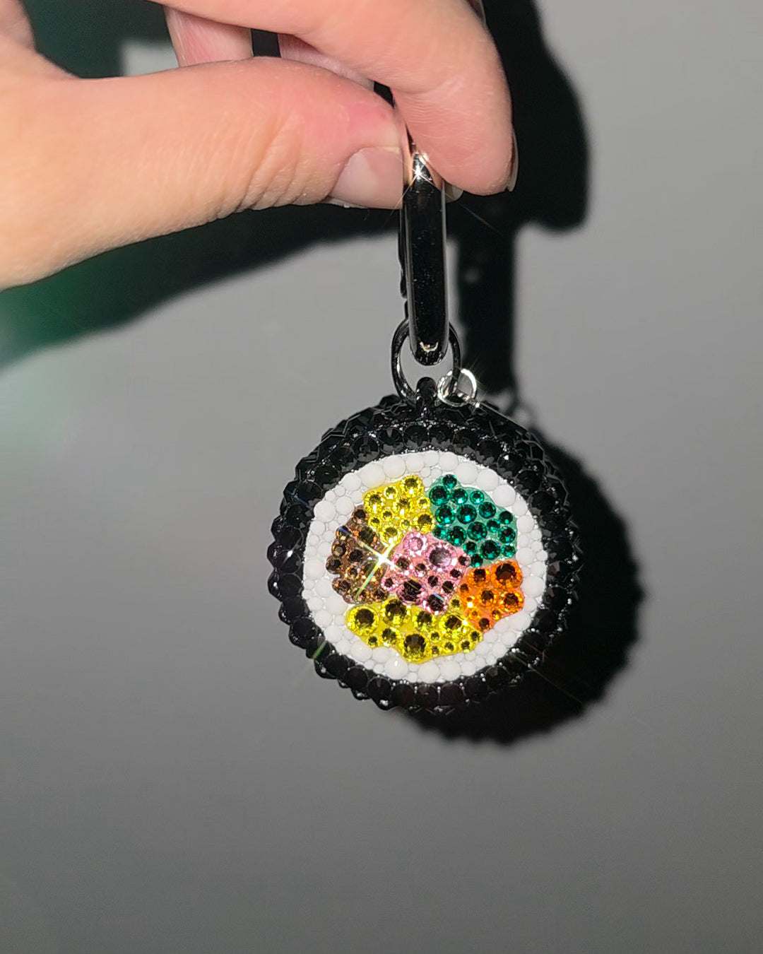 Colorful beaded keychain held by a hand against a neutral background