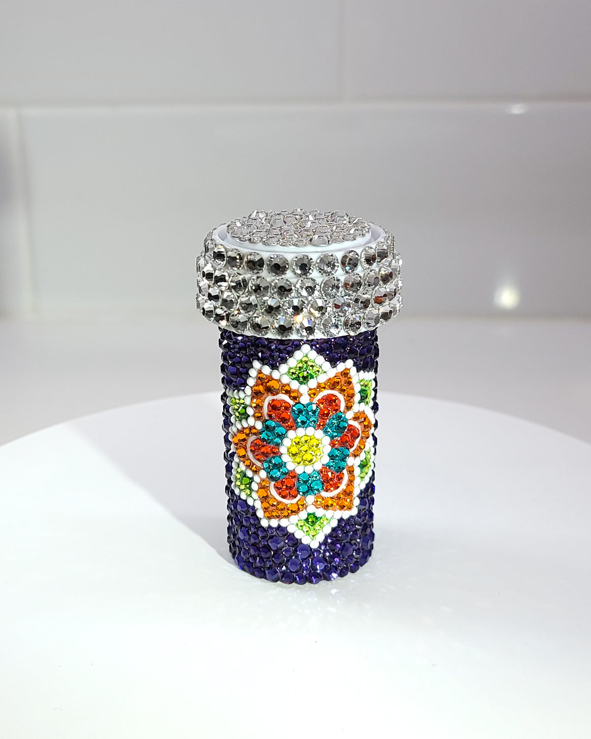 The front of the Dancheong Pill Bottle, a fully rhinestoned pill bottle featuring a large dancheong against a purple background.