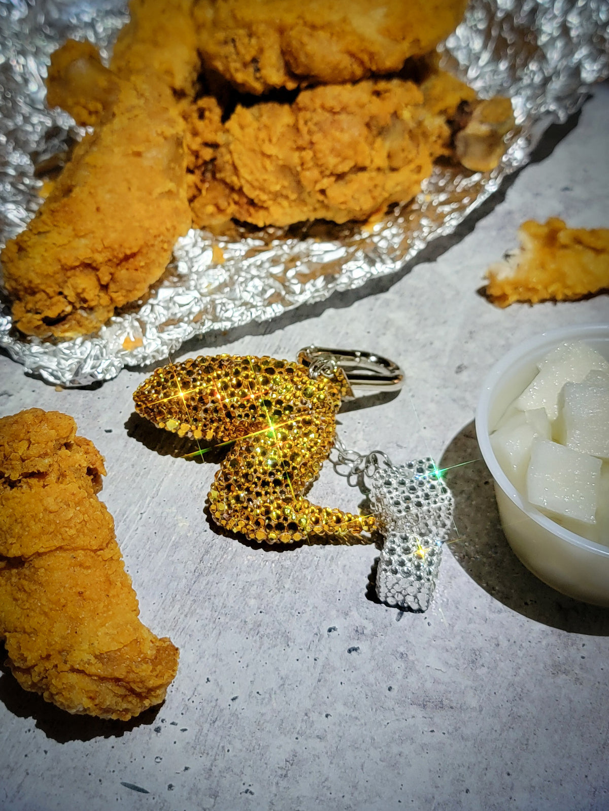 A close-up photo of a chicken wing purse charm covered in rhinestones.