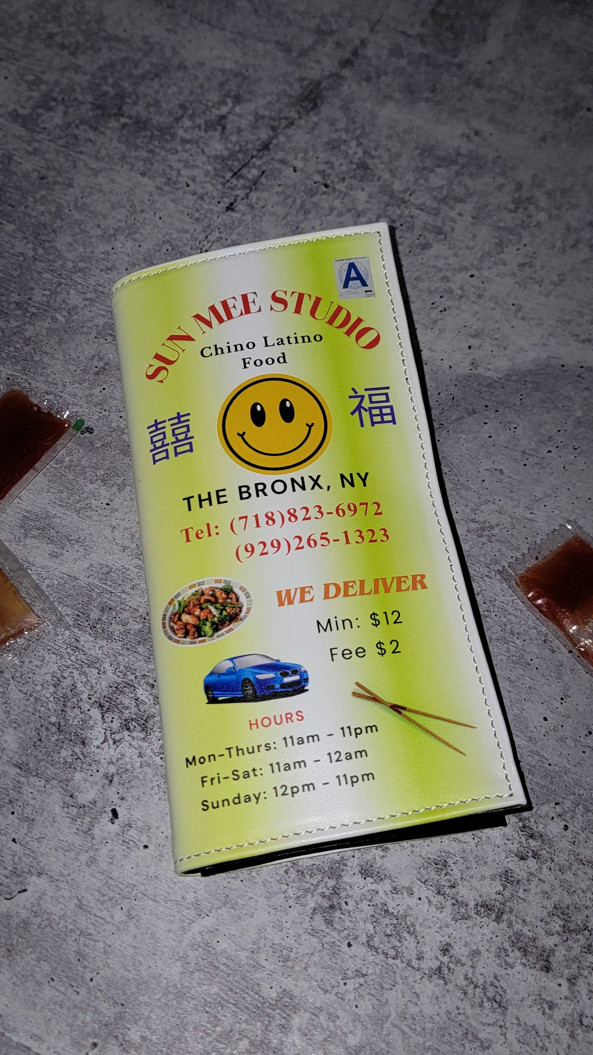 The front of a leather wallet printed in the style of a Chinese takeout menu, against a gray concrete background.