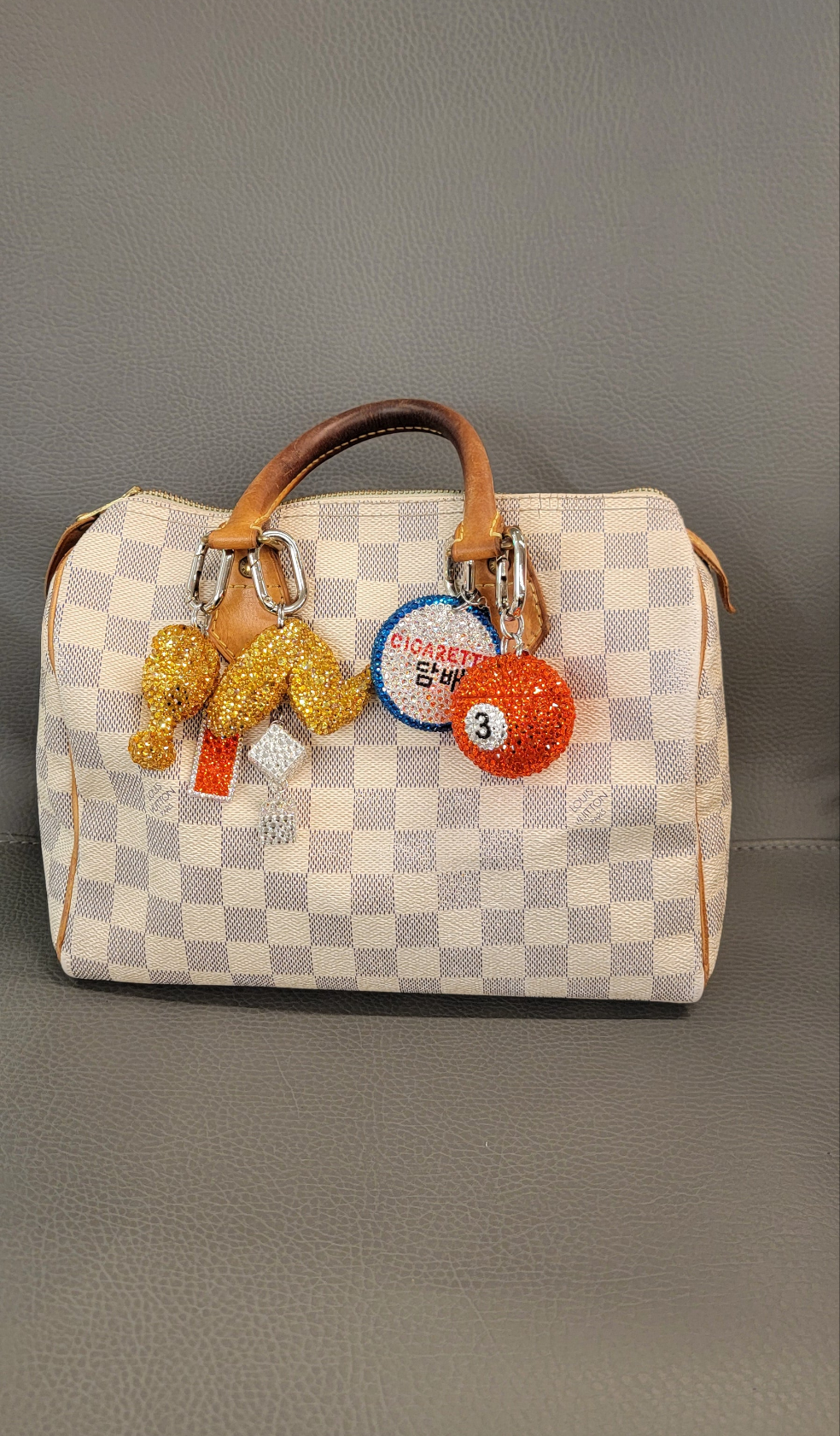The Pool Ball Bag Charm hanging off of a checkered purse against a gray background.