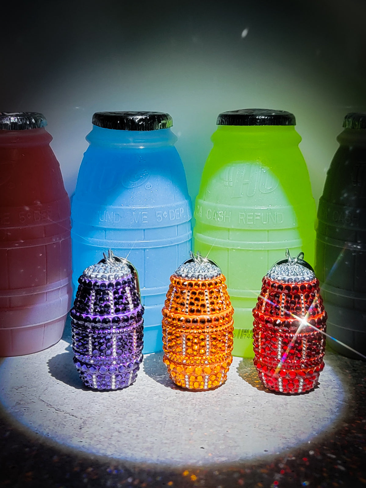 Front picture of three quarter water bag charms: purple, orange, and red. Surrounded by larger quarter waters.
