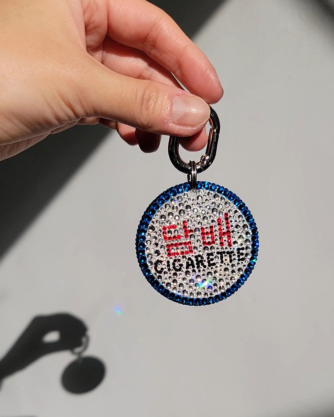 One side of the Nightlife Cigarette Sign Bag Charm, featuring prominent hangul in red, with English writing beneath in black.