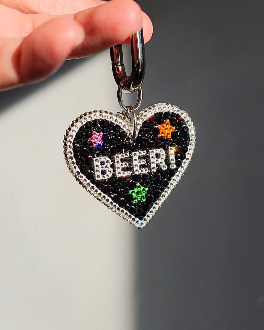 The English side of the Nightlife Beer Sign Bag Charm, against a gray background.