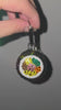 Video of The Gimbap Charm, being spun around to show all angles. The charm is being held up against a gray wall.