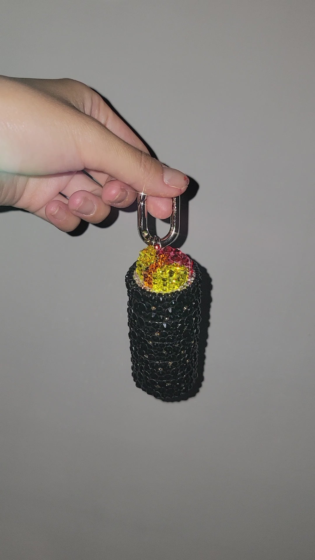 Video of Gimbap Bag Charm being rotated by hand against a gray background.