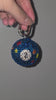 Video of a bag charm resembling a number 2 pool ball covered in rhinestones, being rotated slowly against a gray background.