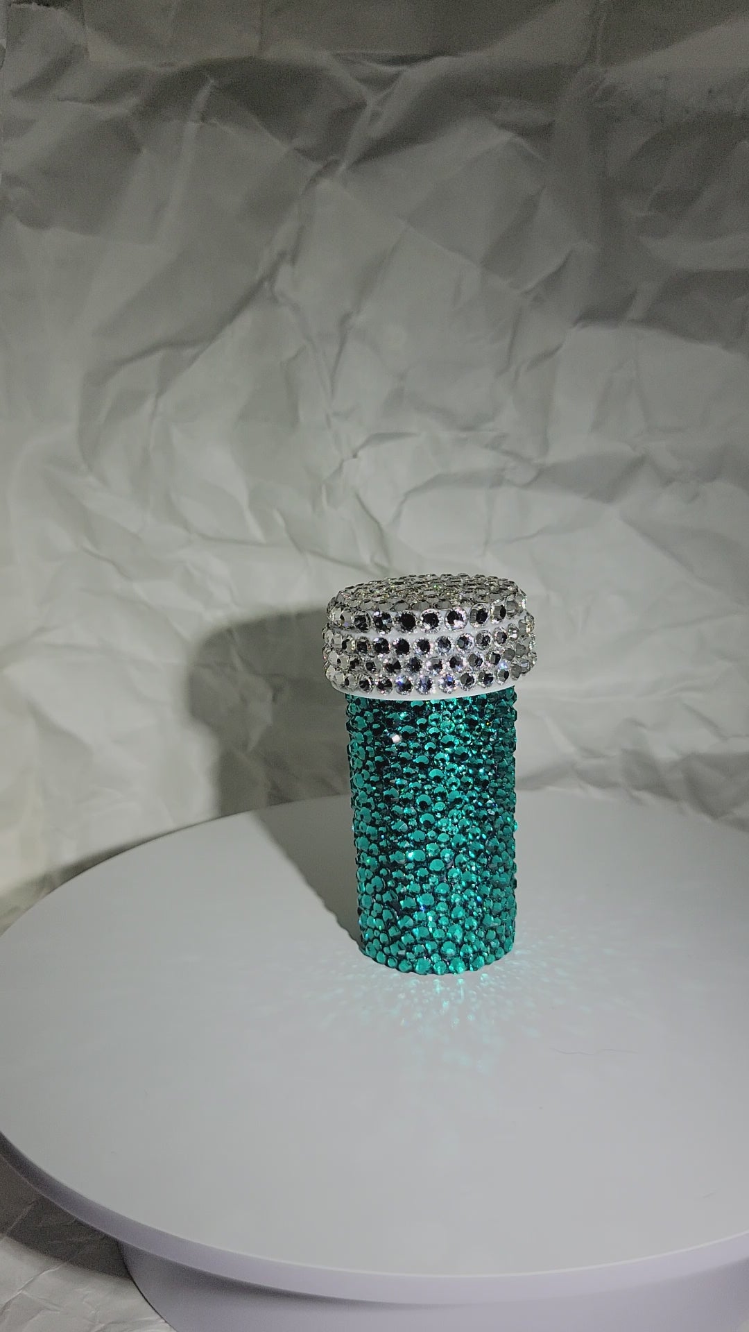 A video of the Smile Harder Pill Bottle being rotated against a white, crumpled paper background.