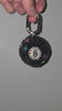 Video of a bag charm resembling an 8 ball covered in rhinestones, being rotated slowly against a gray background.