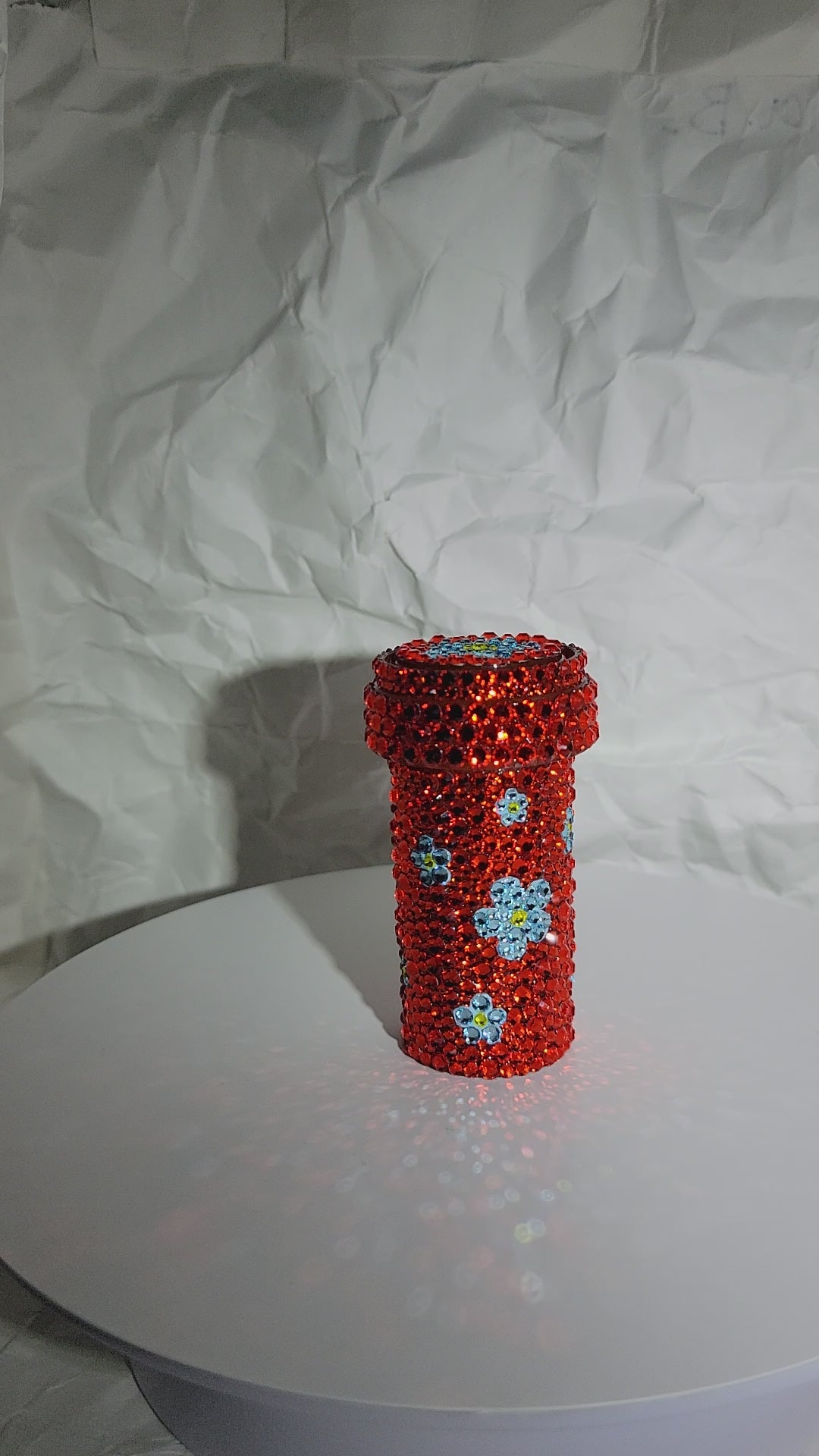 Chueok Pill Bottle being rotated on a white surface, against a white, crumpled paper background.
