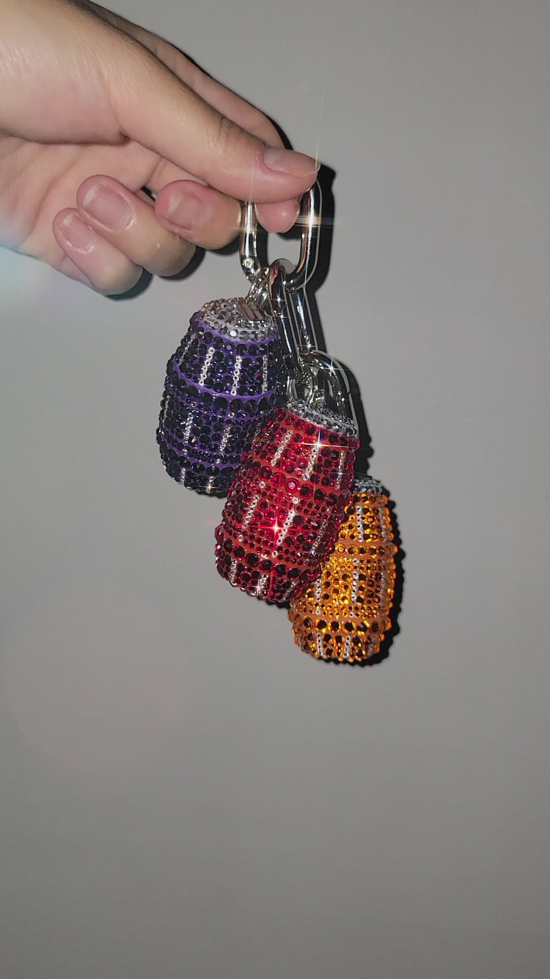 Video of purple, orange, and red quarter water bag charms being held up against a gray background.