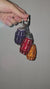 Video of purple, orange, and red quarter water bag charms being held up against a gray background.