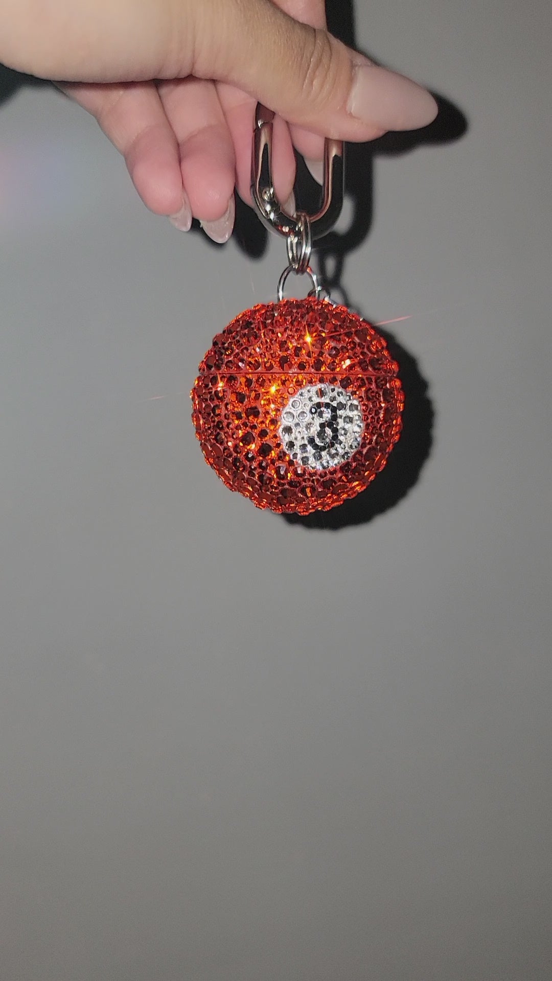 Video of Pool Ball Charm being rotated by hand against a gray background.